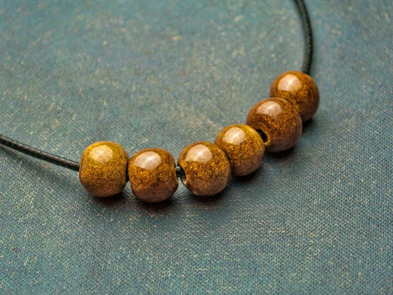May include: A necklace with six brown wooden beads on a black cord.