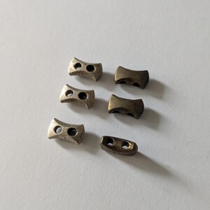 Puede incluir: Seis hebillas deslizantes de metal en dos estilos diferentes. Las hebillas son de color dorado y tienen dos agujeros cada una.