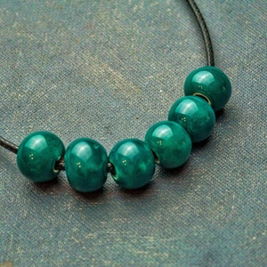 May include: A necklace with six teal green beads strung on a black cord.