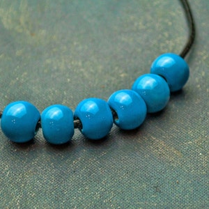 May include: A necklace with six bright blue beads strung on a black cord.
