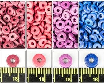 May include: A close-up of four groups of donut-shaped beads. The beads are in four colors: red, pink, purple, and blue. The beads are arranged in a pile, and there is a ruler in the bottom of the image. The ruler is marked with inches.