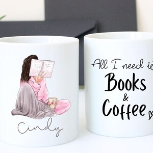 May include: Two white ceramic mugs. One mug features an illustration of a person reading a book, wrapped in a blanket, with the name "Cindy" below. The other mug has the text "All I need is Books & Coffee".