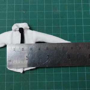 Op de afbeelding: Een wit overhemd met een zwarte stropdas, gemeten met een liniaal. De liniaal toont metingen in inches.