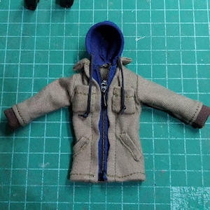 May include: A tan hooded jacket with a blue zipper and blue hood. The jacket has two pockets on the front and a drawstring hood.