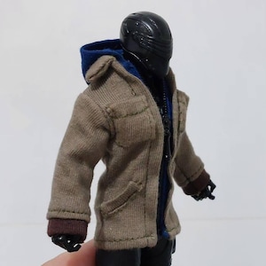May include: A brown hooded jacket with a zip fastening and two pockets. The jacket has a blue lining and brown cuffs. The jacket is being worn by a figure with a black helmet.