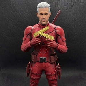 以下が含まれることがあります： 銀髪と赤いスーツを着た赤いアクションフィギュアで、2丁の金色の玩具銃を持っています。フィギュアは黒いベルトとポーチが付いています。刀が背中に巻き付けられています。