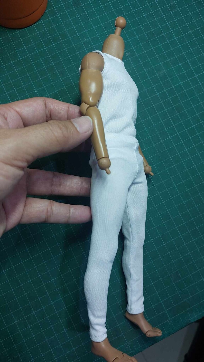 K&ouml;nnte beinhalten: Ein wei&szlig;es &auml;rmelloses Hemd und eine wei&szlig;e Hose an einer Gelenkfigur mit brauner Haut. Die Figur ist mit einem am Ellbogen gebeugten Arm posiert.