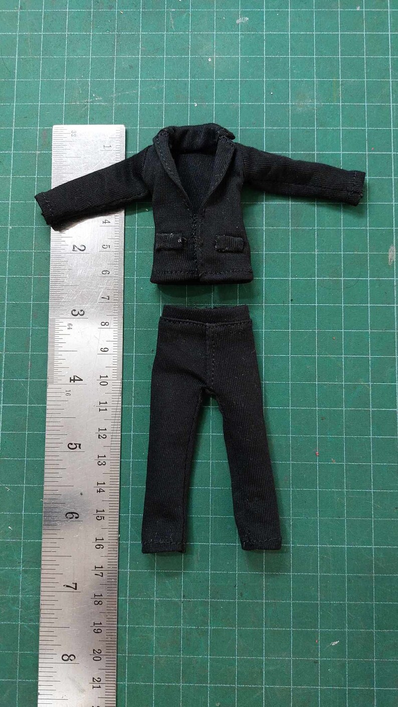 Op de afbeelding: Een zwart pak met een jas en broek. De jas heeft een kraag en lange mouwen. De broek heeft een rechte pijp.