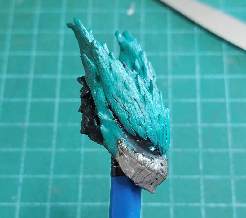 Pu&ograve; includere: Una figura in miniatura dipinta in turchese e argento di una creatura con una testa spinosa e piumata. La figura &egrave; montata su un bastone blu.