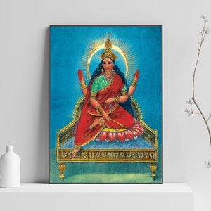 May include: A painting of a Hindu goddess sitting on a throne with a blue background. She is wearing a red sari and a green blouse. She has four arms and is holding a sword and a lotus flower.