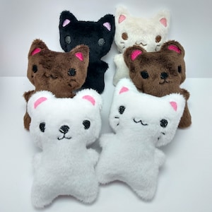 May include: Five plush cat toys in different colors. The toys are white, brown, black, and cream. Each toy has embroidered eyes, a nose, and a mouth.