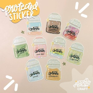 May include: A collection of Citadel Colour stickers in various colors, including pink, green, and brown, with glitter accents. Each sticker features the Citadel Colour logo and a unique color name. The stickers are arranged on a light pink background with decorative elements.