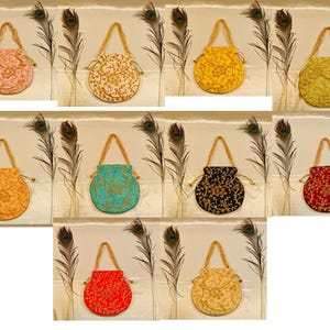 Puede incluir: Una colección de bolsos bordados con cordón en varios colores, incluyendo rosa, crema, amarillo, verde, naranja, turquesa, negro y rojo. Cada bolso presenta un asa dorada y intrincados diseños florales. Los bolsos se exhiben con plumas de pavo real.