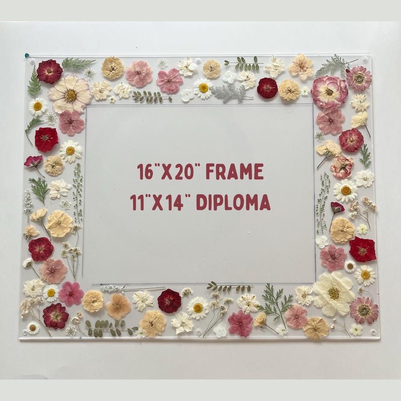 Pode incluir: Uma moldura de acr&iacute;lico transparente decorada com flores secas em tons de vermelho, rosa, amarelo e branco. A moldura est&aacute; rotulada como "16"X20" FRAME" e "11"X14" DIPLOMA".