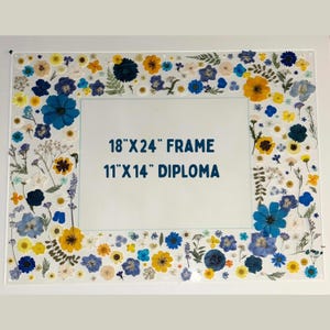 Pode incluir: Uma moldura de acr&iacute;lico transparente, 45.7 cm x 61 cm, decorada com flores secas em tons de azul, amarelo e branco. A moldura &eacute; projetada para um diploma de 27.9 cm x 35.6 cm. As flores s&atilde;o dispostas ao redor das bordas da moldura.