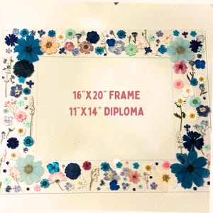 Pode incluir: Uma moldura retangular transparente decorada com flores secas em tons de azul, rosa e branco. A moldura est&aacute; rotulada como "16"X20" FRAME" e "11"X14" DIPLOMA". Medidas: 40,6 cm x 50,8 cm.