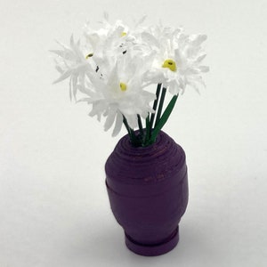 Peut inclure: Un bouquet de fleurs en papier blanc avec des centres jaunes dans un vase violet.