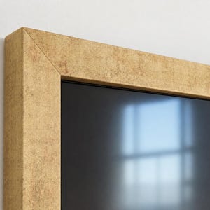 Può includere: Una cornice rettangolare caratterizzata da una finitura metallica dorata testurizzata dall'aspetto usurato. La cornice presenta un profilo piatto e largo con angoli a 45 gradi e racchiude una superficie scura e riflettente con riflessi.
