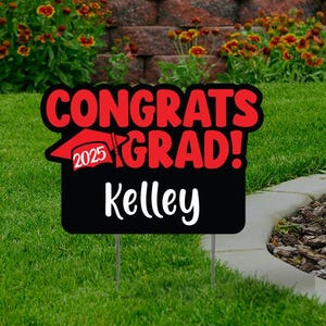 May include: Red and black yard sign with the text "Congrats Grad!" and a graduation cap with the year 2025. The name "Kelley" is written below the text.