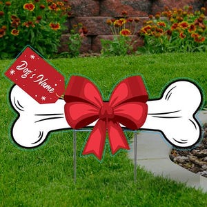 May include: A white bone-shaped yard sign with a red bow and a red tag that says "Dog's Name".