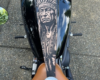 May include: Black motorcycle with a brown leather seat. The gas tank features a detailed graphic of a Native American chief in shades of brown and black. The motorcycle has a chrome fuel cap and handlebars.