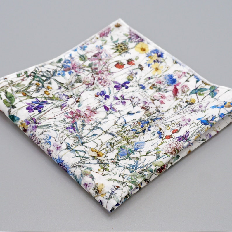 May include: A white cotton pocket square with a floral pattern featuring a variety of colorful flowers and leaves.