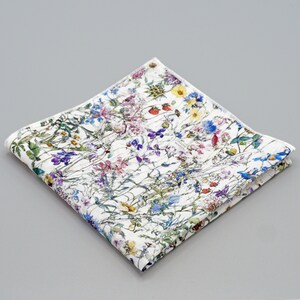 May include: A white cotton pocket square with a floral pattern featuring a variety of colorful wildflowers, including blue, purple, pink, yellow, and green.
