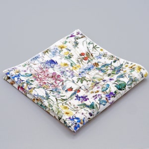 May include: A white cotton handkerchief with a floral print featuring a variety of colorful flowers and green leaves.