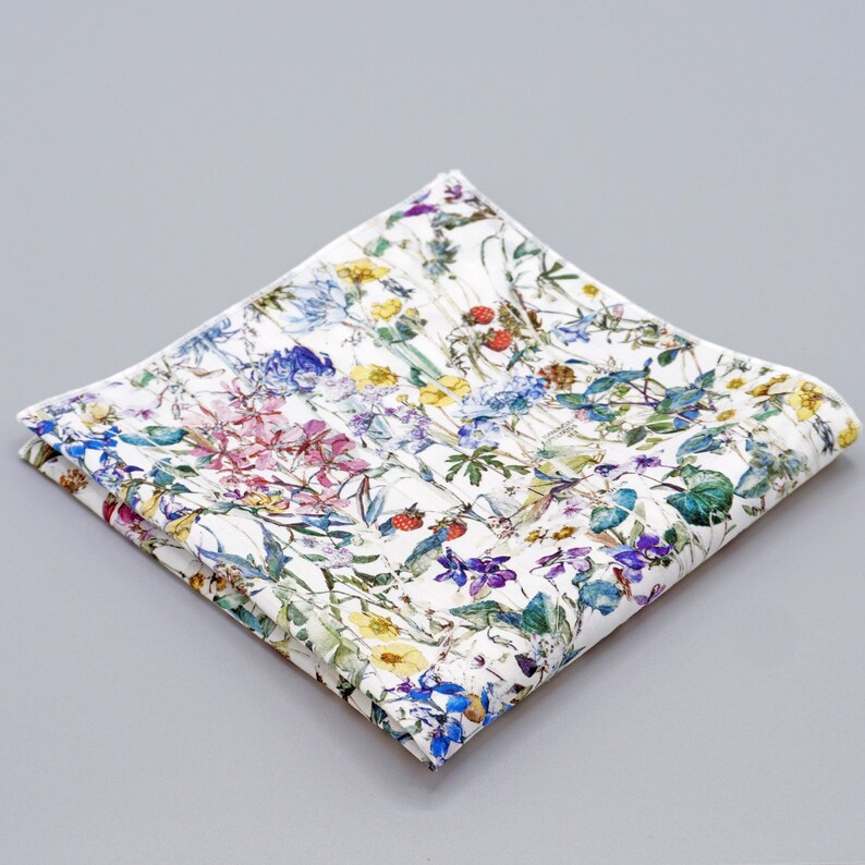 May include: A white cotton handkerchief with a floral print featuring a variety of colorful flowers and green leaves.