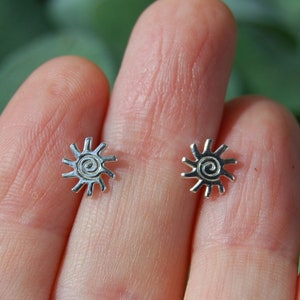 Op de afbeelding: Een paar zilveren oorbellen met een zonontwerp. Elke oorbel heeft een spiraal in het midden van de zon.