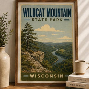 May include: A framed vertical poster featuring a landscape illustration of Wildcat Mountain State Park in Wisconsin. The artwork depicts a winding river through a forested valley, rocky cliffs, and a pine tree under a blue sky with clouds.