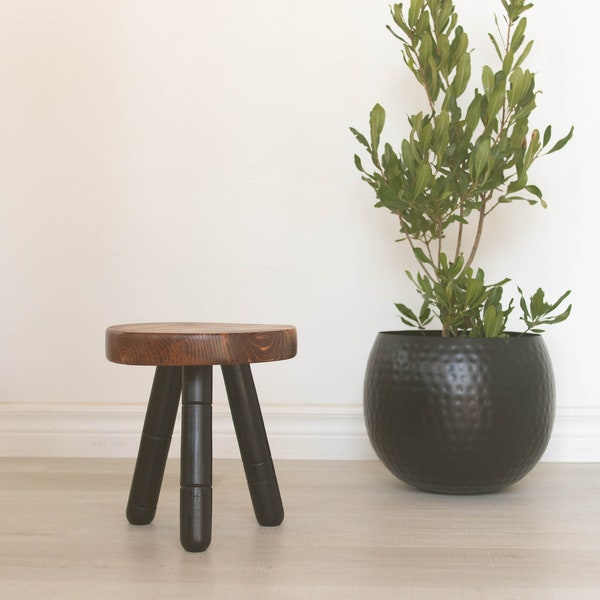 Tabouret trépied à pieds noirs fabriqué à partir de bois récupéré. Petit tabouret trépied moderne bicolore. Pieds noirs, tabouret brunâtre à dessus rouge