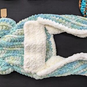 May include: A blue and green knitted hooded dog sweater with a white fleece lining.