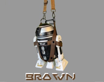 May include: A white and black R2-D2 style robot with brown straps attached to it. The robot is hanging from the straps. The text "BROWN R-SERIES" is printed below the robot.