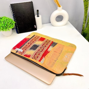May include: A laptop sleeve with a zipper closure. The sleeve is made of a patchwork fabric with a colorful geometric pattern in shades of red, yellow, and blue. The text "ART-5815" is printed on the sleeve.