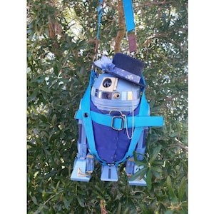May include: A blue and white robot wearing a blue suit and a black top hat with a blue and white patterned band. The robot is hanging from a blue strap.