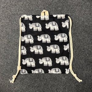 May include: Black drawstring bag with a white elephant pattern. The bag has a white drawstring and is made of a soft, cotton fabric.