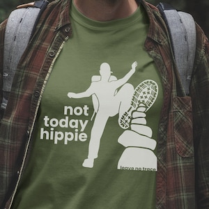 May include: A green t-shirt with a white graphic of a person stepping on a pile of rocks with the text "not today hippie" and "leave no trace" below the graphic.