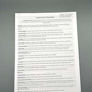 May include: A white sheet of paper with a list of different types of crystals and their metaphysical properties. The list is organized alphabetically by crystal name. The paper has a title at the top that reads "Crystal Guide / Cheat Sheet".