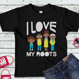 Puede incluir: Camiseta negra con el texto "I LOVE MY ROOTS" en blanco. Cuatro figuras de dibujos animados de personas con piel morena y cabello negro están de pie en fila debajo del texto. Las figuras visten ropa colorida.