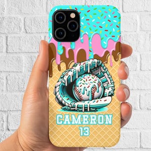 May include: A phone case featuring a baseball theme with a playful design. The top has a turquoise sprinkle pattern, with pink and brown drips. A baseball mitt holds a baseball with sprinkles. The name "CAMERON" and the number "13" are displayed.