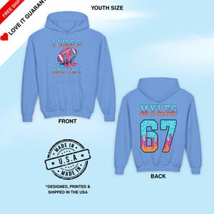 May include: Light blue youth hoodie with a front graphic of a football with the text "I WAS 6 NOW I'M 7". The back of the hoodie has the name "MYLES" and the number "67". The hoodie is made in the USA.