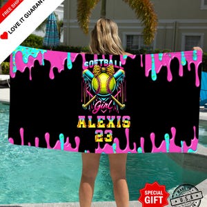 Könnte beinhalten: Ein schwarzes Softball-Handtuch mit einem rosa und türkisfarbenen Tropfdesign. Das Handtuch zeigt eine Softball-Grafik mit dem Text "SOFTBALL GIRL ALEXIS 23". Das Handtuch ist ein besonderes Geschenk.