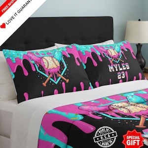 May include: Black bedding set with a baseball theme. The set includes two pillowcases and a comforter, featuring a baseball design with pink and teal dripping accents. The pillowcase has the name "MYLES" and the number "23".