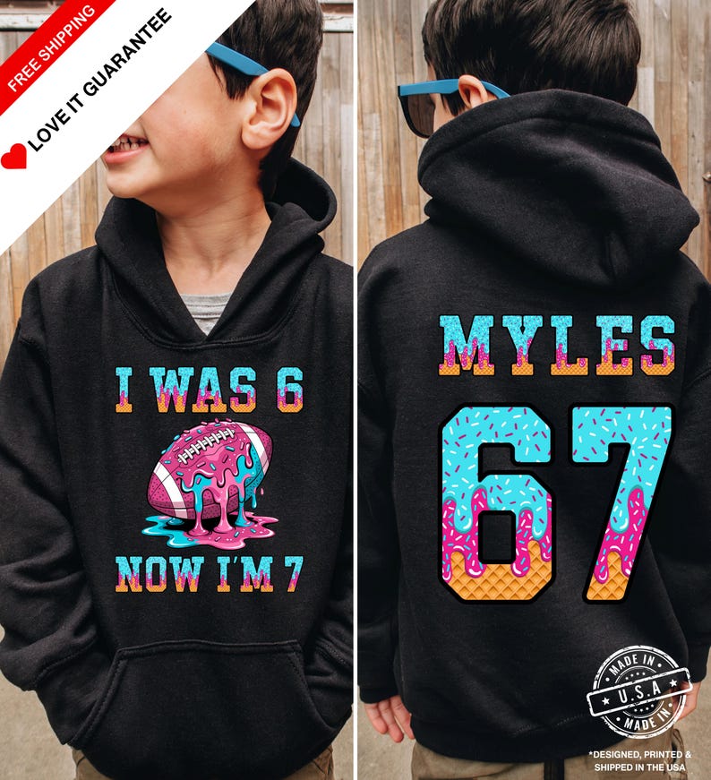 May include: Black hoodie with a colorful graphic. The front says "I WAS 6 NOW I'M 7" with a football design. The back has "MYLES" and the number "67" in a blue and pink design. Made in the USA.