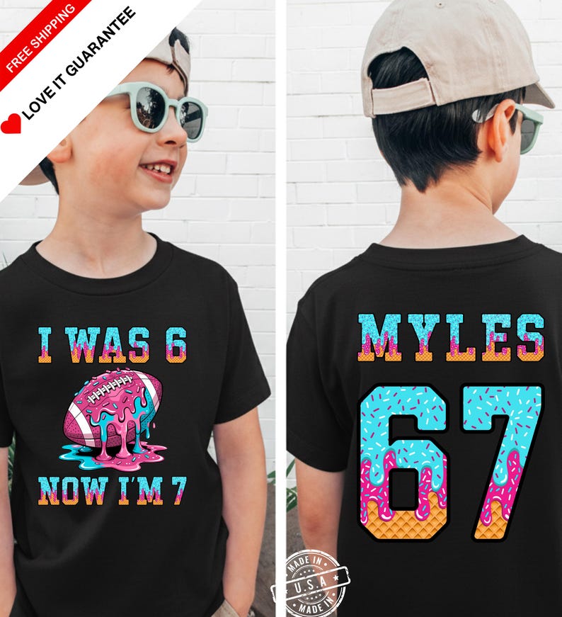 May include: Black t-shirt with a colorful football graphic and the text "I WAS 6 NOW I'M 7" on the front. The back of the shirt has the name "MYLES" and the number "67" in a similar colorful design. A fun birthday shirt.