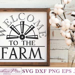 May include: A white wooden sign with black text that reads "Welcome to the Farm". The sign features a black silhouette of a windmill.