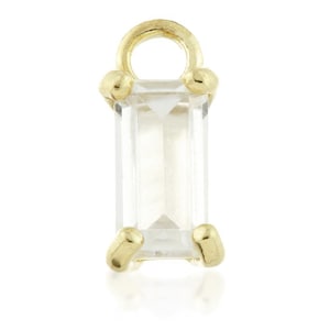 May include: Gold charm with a clear rectangular gemstone. The charm has a loop at the top for attaching to a necklace or bracelet.