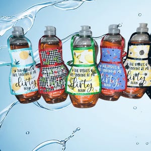 May include: Five colorful dish soap bottles with aprons attached. The aprons have a variety of patterns and say "The dishes are looking at me, dirty again".