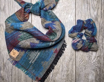 May include: A blue, green, red, and brown patterned bandana with black fringe and a brown leather tag that says "ruff  wear". A matching blue, green, red, and brown patterned scrunchie is also pictured.